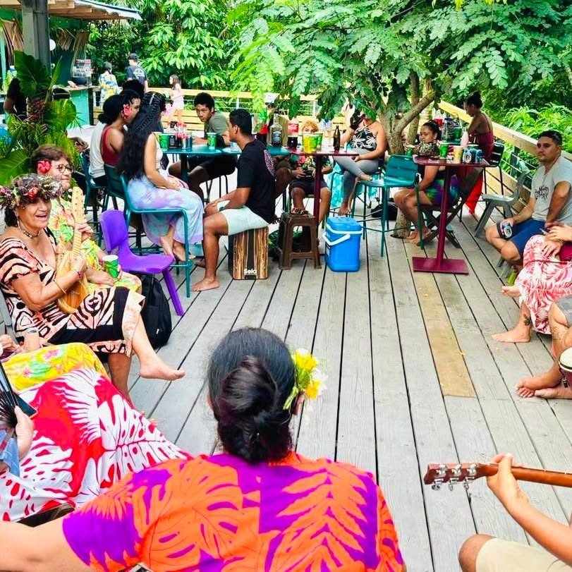 Musiciens et convives en chemises fleuries sur la terrasse en bois